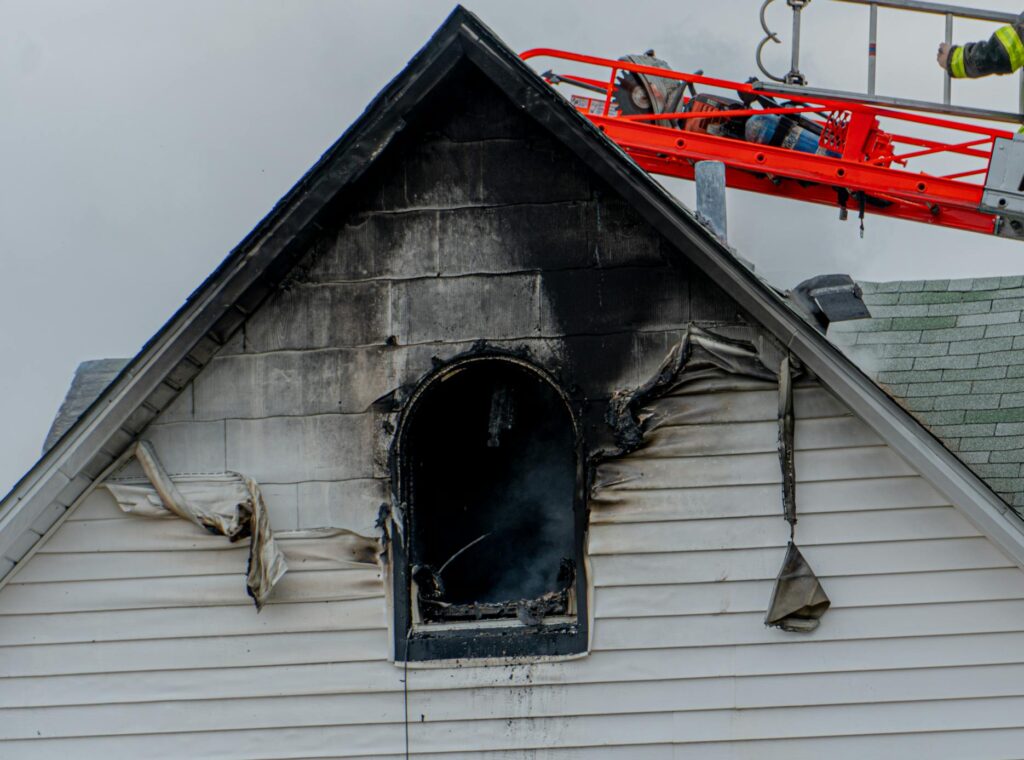 Firefighter on ladder tackling a residential roof fire in Baltimore city.