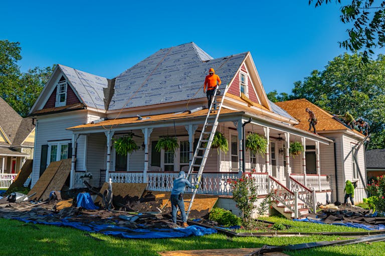 Roofers replace the roof of a historic home in Weatherford, Texas.